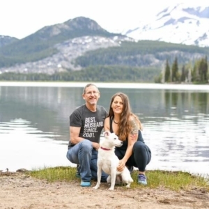 Plant based couple with white dog in front of a beautiful mountain